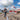 Man holding and looking at a 14 foot siding sheet metal piece he just bent on an Innovatools bending machine, with a red barn and farm silos in the background.