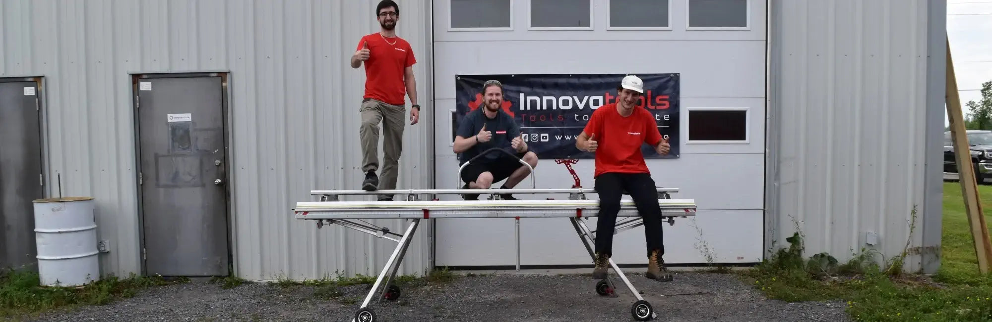 Three Innovatools employees on top of a siding brake mounted on a collapsible stand to prove sturdiness